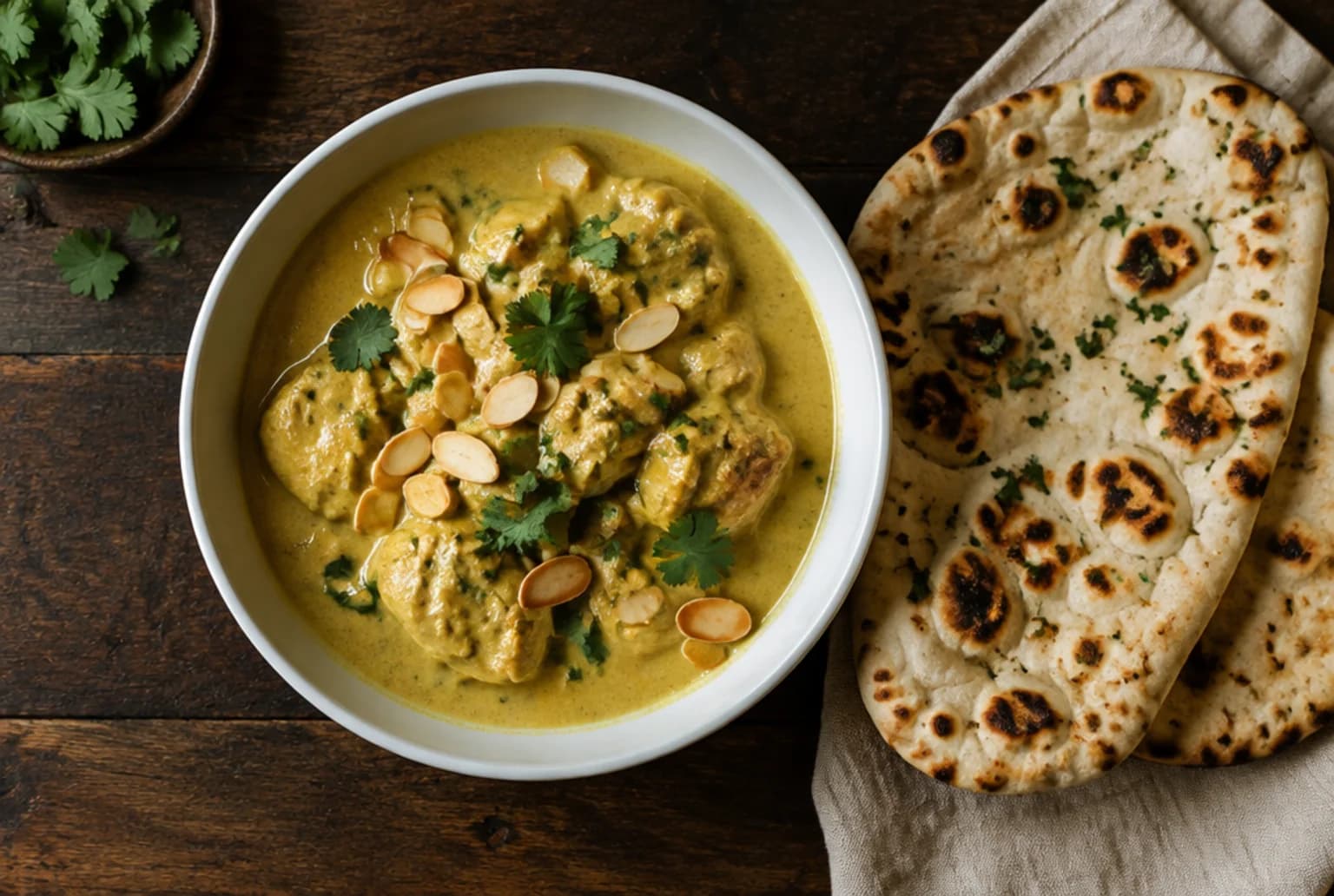 Chicken Korma in einer weissen Schüssel: cremig goldene Sauce mit Pouletstücken und Mandelblättchen