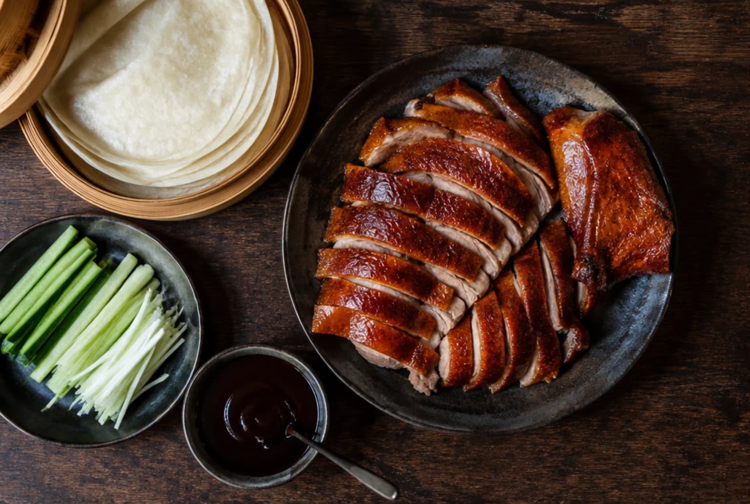 Knusprige Peking-Ente: glänzend tranchierte Entenscheiben mit Pfannkuchen, Gurke und Hoisinsauce